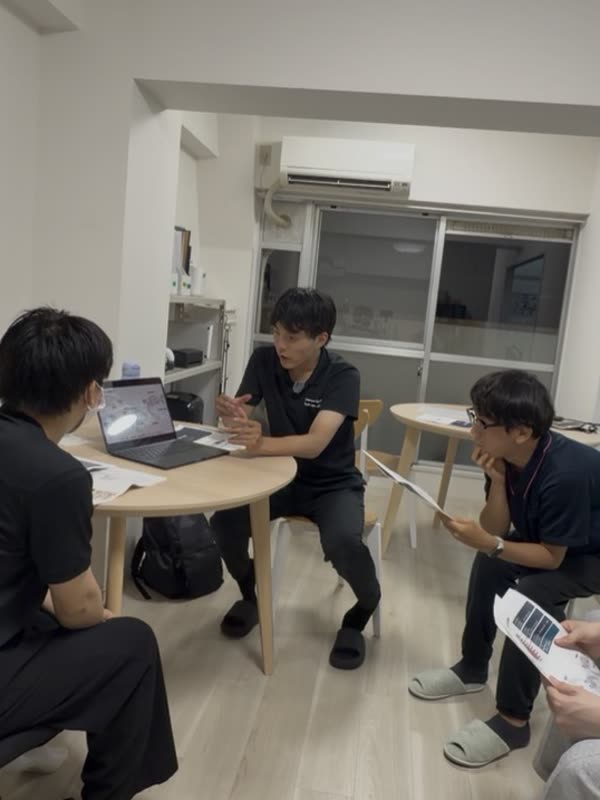 丸テーブルを囲み、資料とノートパソコンを見ながら四人で症例について話し合っている様子